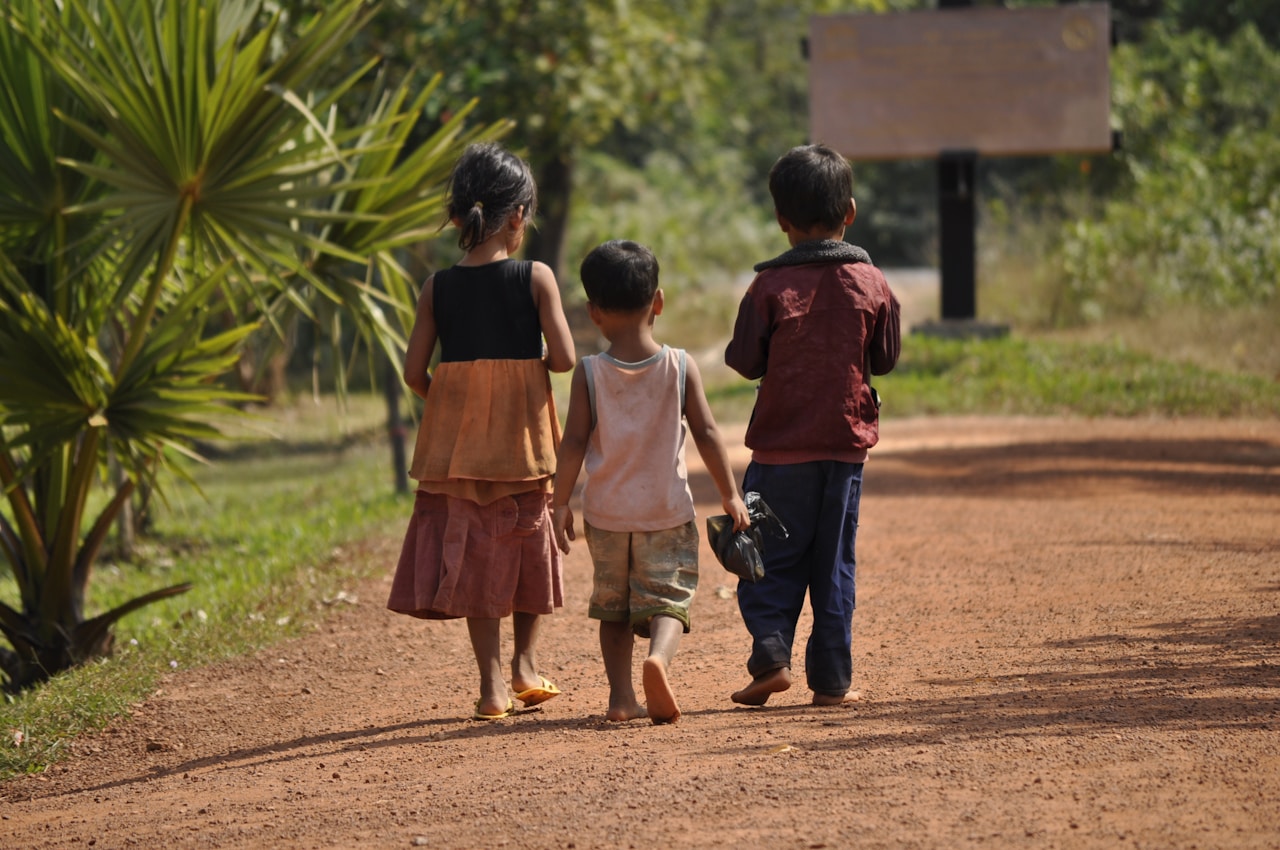 Three children walking along a dirt path