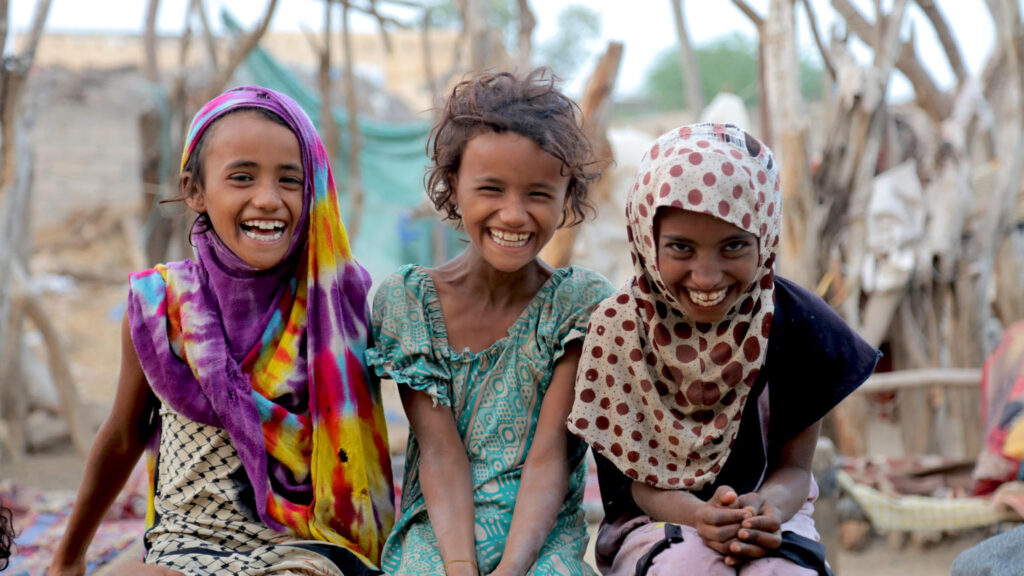 Three smiling children in a community